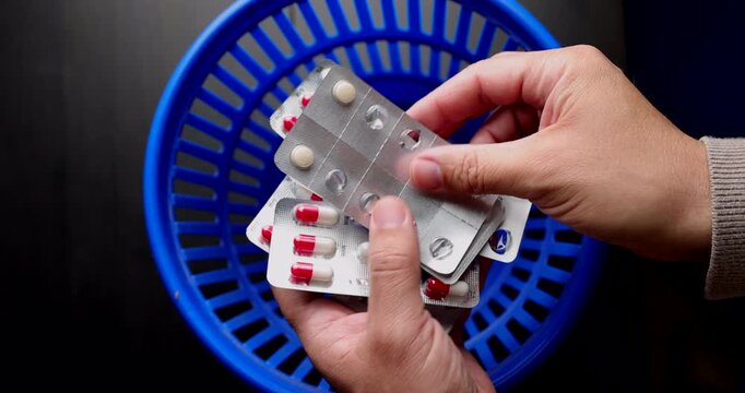 A patient throwing away several pill blisters into a blue recycling bin showing medical malpractice and incorrect drug management.