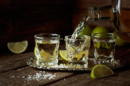 Tequila with salt and lime slices on a silver tray.