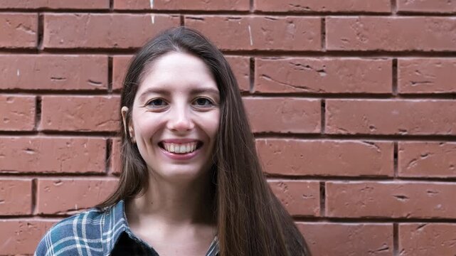 A surprised, delighted woman. An impressed woman tries to attract attention. Sales concept, a compelling offer. An enthusiastic girl against a brick wall.
