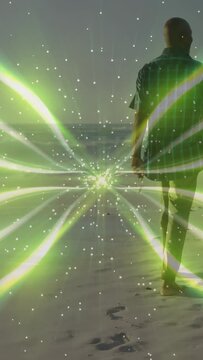 Vertical video: Man walking toward shore, green pulse sparking VFX overlay overlapping silhouette