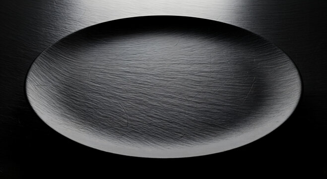Empty black plate with textured surface on dark background, minimalist fine dining restaurant menu presentation, gourmet food styling, moody lighting, modern interior backdrop.