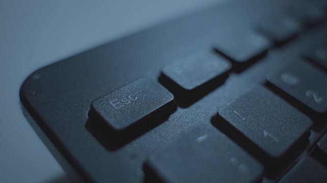 Close up as finger presses Escape key on keyboard various times frantically. Person clicking on Esc command key multiple times in fast rapid motion. Nervous or stressed exiting task or ending session
