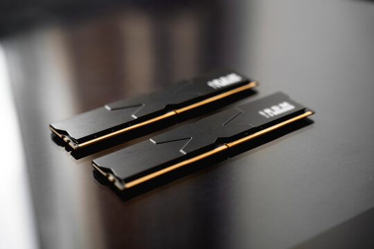 Black DDR5 RAM memory modules placed on a dark, glossy surface. RAM shortages on the market, rising prices, and increased demand driven by the growing need for AI training.