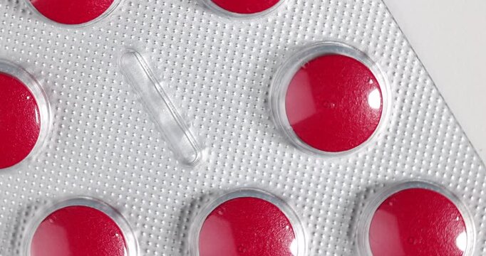 Detailed zenithal perspective of rotating red medicine blisters for chronic disease management and nutritional wellness treatments.