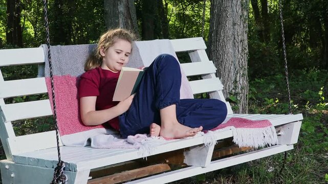 Boy enjoys peaceful reading outdoors. Kid studies with happiness and focus. Child reads book in nature setting. Boy enjoys imagination through reading. Kid sits and reads during leisure time.