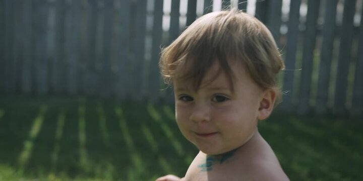 Toddler standing in a grassy backyard on a summer day