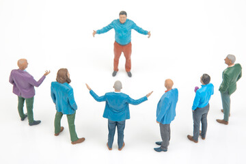 Naklejka premium Miniature people in a group discussion with one person leading from the center wearing a bright blue shirt