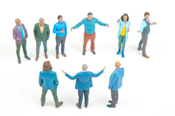Fototapeta premium Miniature people gather and engage in conversation in a small group setting during daytime with a white background