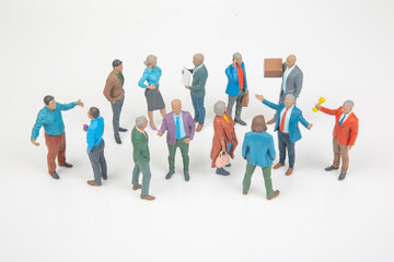 Fototapeta premium Miniature people in a group talking and interacting in a social setting during the day at a neutral background