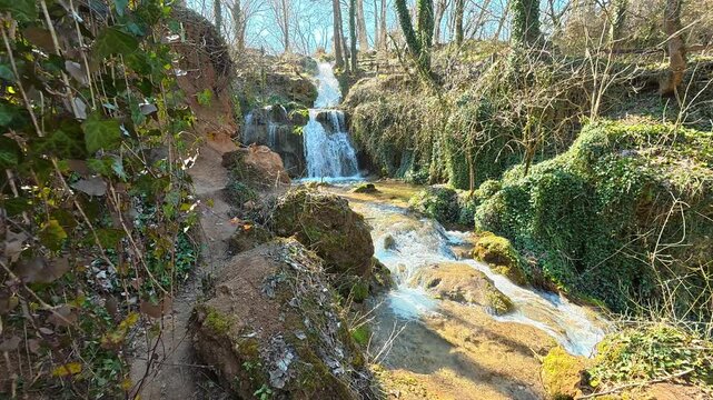 Waterfall Reveal Through Green Ivy Leaves in Sunny Autumn Forest. Ozren Mountain, Sokobanja region. Balkans, Serbia.