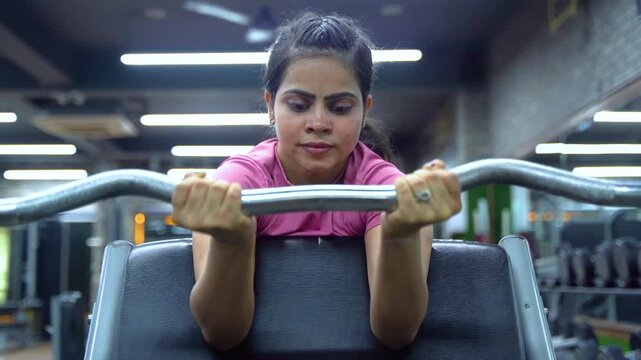 Indian Woman Performing EZ Bar Preacher Curl for Biceps Workout in Modern Gym