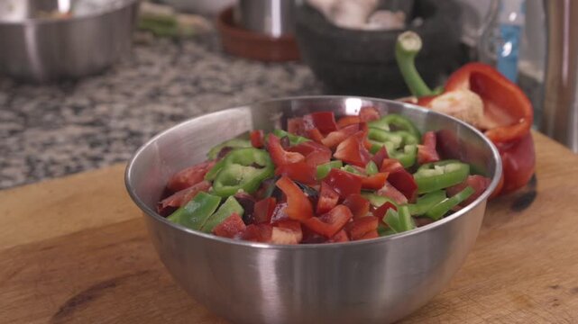 Chopped tomatoes and green peppers in bowl on kitchen cutting board