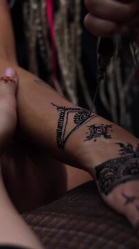 Close up of traditional henna tattoo artist drawing decorative pattern on hand showing cultural body art ritual in Morocco