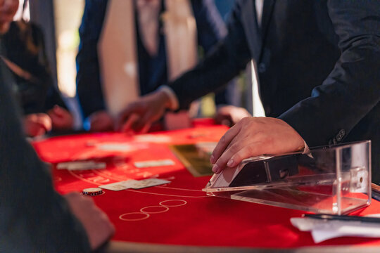 Casino dealer dealing cards on blackjack table with players around. Gambling, risk and betting concept.