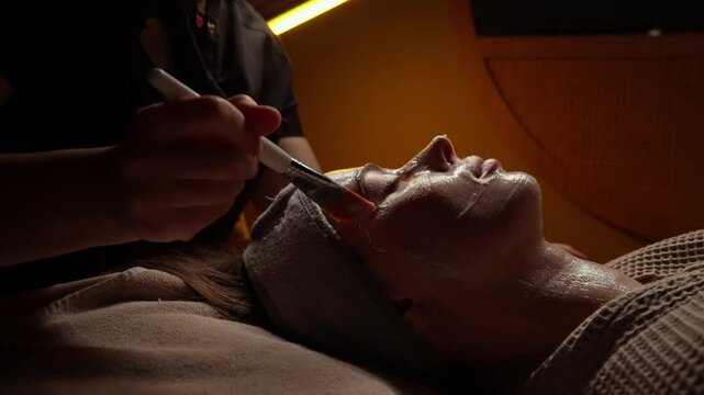 Relaxing spa facial treatment with soothing mask application under warm ambient lighting, highlighting serene skincare routine and professional pampering experience
