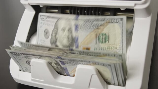 Money counting machine processing dollars bills in motion. Counting hundred dollar bills in banking machine. Device counting paper money in motion. Automatic counting dollars for business clip.