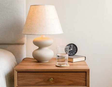 A stylish bedside table featuring a lamp and a glass of water.