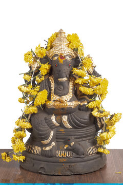 Ganesha idol decoration with gold colored coating and yellow marigold garland for Hindu rituals