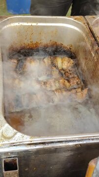 Szaszłyki w zalewie w pojemniku na jarmarku, uliczne jedzenie na patykach w dymnej atmosferze, stoisko gastronomiczne.
