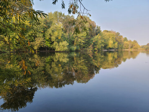 Vibrant Autumn Foliage Perfectly Reflected in Calm Still Lake Water on Clear Morning