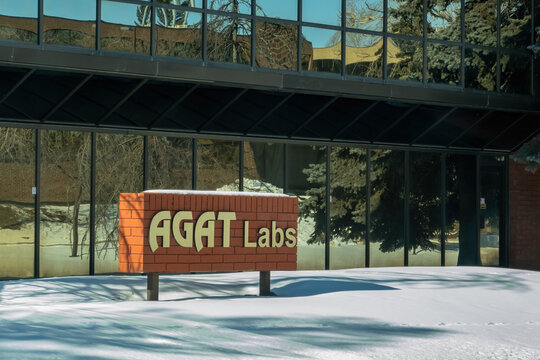 Calgary, Alberta, Canada. March 21, 2026. The AGAT Labs monument sign stands in front of a glass-walled office building during a sunny winter day.