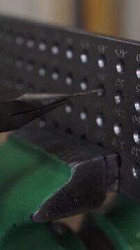 A person is using a pair of pliers to open a small box with a bunch of small hol