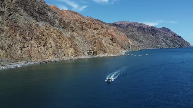 Aerial tracking shot of a tourist boat in la ventana, Baja California - Mountains and seagull flying by drone