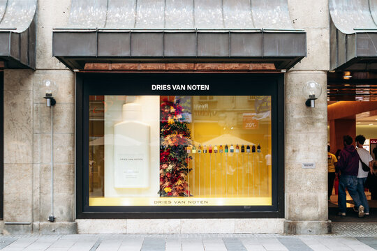 Munich, Germany - April 15, 2025: Dries Van Noten storefront display with perfume bottles and decorative installation behind a large glass window in the city center
