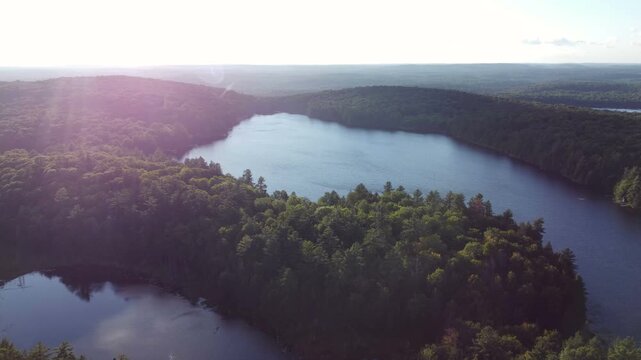 Flying over Buckskin Lake on a late summer afternoon towards the expansive wilderness of crown land located in the Tory Hill area of Highlands East, in southern Ontario, Canada. With some lens flare,.
