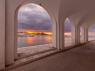Fototapeta premium Harbor view through white arches at sunrise in Cadaques, Catalonia, Spain