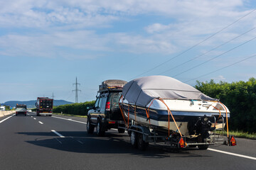 Big luxury cabin motorboat cruiser yacht trailer auto SUV carrier river lake highway road sunset summer light. Luxury rich fishing leisure recreation lifestyle. Service maintenance transportation © Kyryl Gorlov