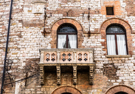 Brick facade with a picturesque balcony of Palazzo Ajo on Via Cesare Fani (formerly Via della Chiavica), a historic noble palace in the old town of Perugia, Umbria, Italy. 