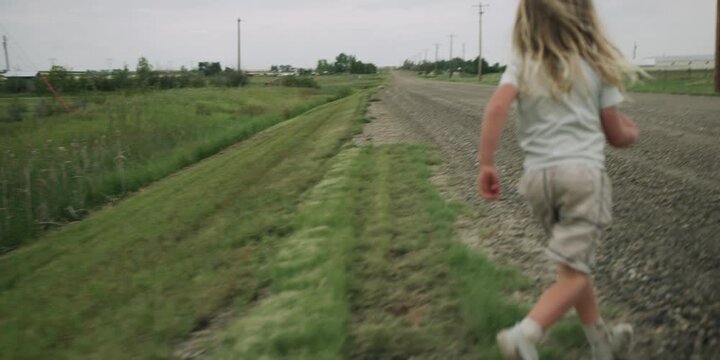 Young boy running along a grassy country road