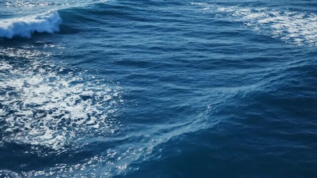 Top view aerial ocean water surface with rolling sea waves deep blue ocean tones white foam highlights natural fluid motion realistic water texture sunlight sparkle across moving water cinematic smoot