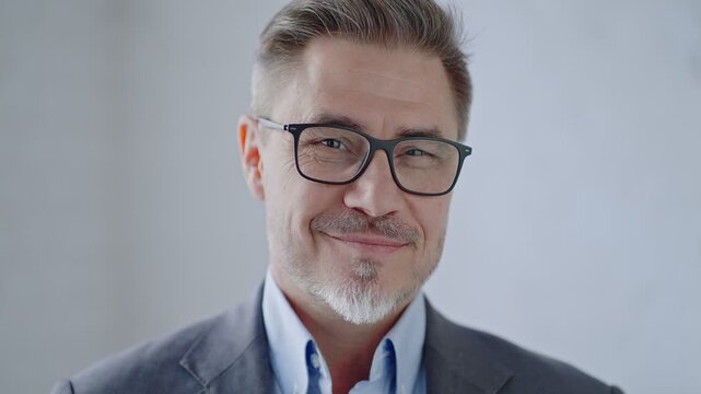 Middle age corporate businessman in business casual. Entrepreneur in shirt and jacket. Mid adult, mature age man, happy smiling. Portrait against white brick wall with copy space.