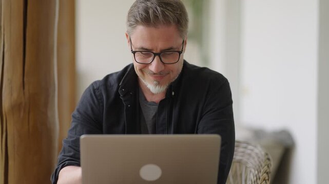 Casual middle age man sitting in garden working on laptop computer in home office. Businessman tele working