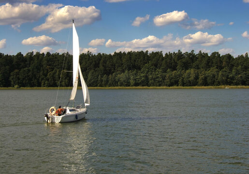 Lonely small sailboat on a lake on a sunny summer day, Poland, Masuria.