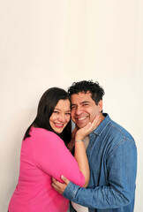 Fototapeta premium Latino man and woman in their 40s show their love to celebrate Valentine's Day and their anniversary with kisses and hugs, laughing and smiling