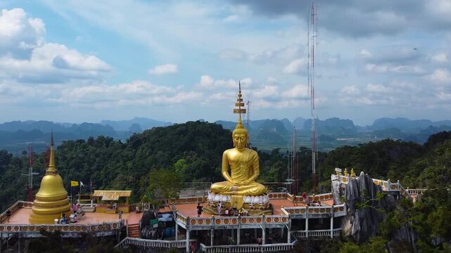 Close drone pullback from a golden Buddha statue at Wat Tham Suea temple in Krabi Thailand.