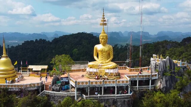 Drone footage starting close to Buddha face and pulling back to reveal Wat Tham Suea temple in Krabi Thailand.