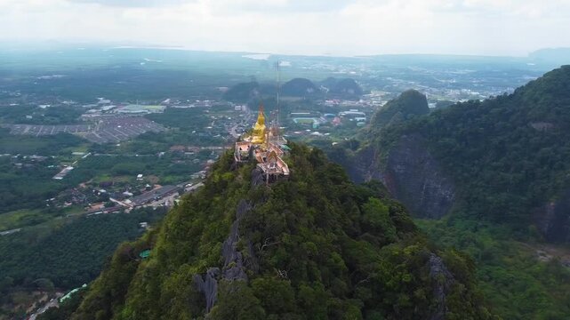 Aerial drone orbit showing Wat Tham Suea temple surrounded by green mountains in Krabi Thailand.
