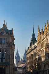 Obraz premium Historic architecture of Prague featuring ornate buildings and spires under a clear blue sky, showcasing the city's rich cultural heritage and urban landscape