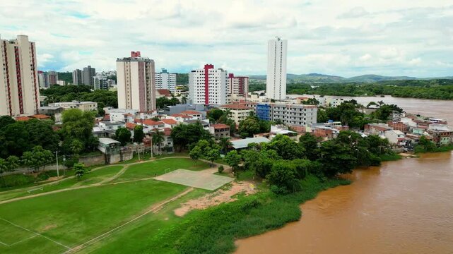 Aerial drone flyover of the city of Governador Valadares, Minas Gerais, Brazil, located along the banks of the Doce river. The footage captures the cityscape, surrounding riverfront, and key landmarks