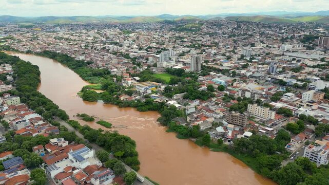 Aerial drone flyover of the city of Governador Valadares, Minas Gerais, Brazil, located along the banks of the Doce river. The footage captures the cityscape, surrounding riverfront, and key landmarks