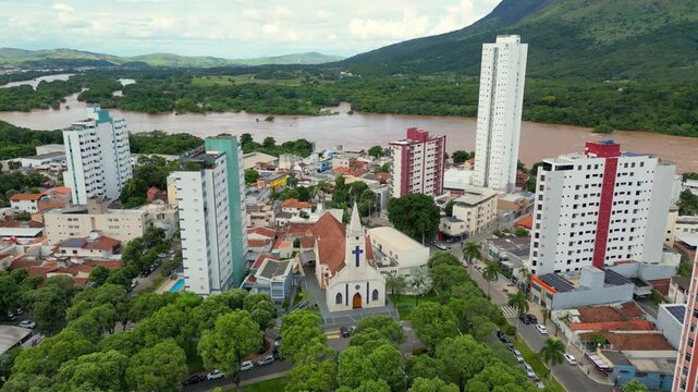 Aerial drone flyover of the city of Governador Valadares, Minas Gerais, Brazil, located along the banks of the Doce river. The footage captures the cityscape, surrounding riverfront, and key landmarks