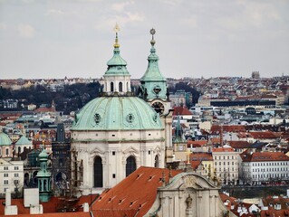 Obraz premium Architectural elements adorn layered city skyline. Sunlit view of ancient bell towers and tiled rooftops