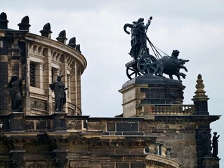 Mythological bronze chariot on building edge. Dramatic sculpture of horses and driver against stormy sky © Vladimir