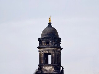 Weathered bell tower under cloudy sky. Historic stone steeple with archways and ornamental features © Vladimir