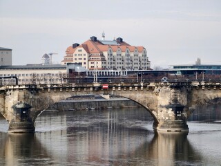 Timeless stone bridge stretching across serene water with nearby city skyline and subtle figures © Vladimir