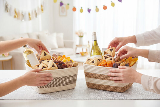 Hands exchanging mishloach manot baskets with wine and cookies